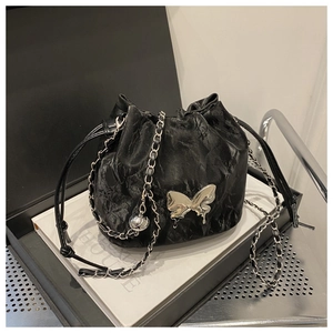 Détail du sac seau noir texturé avec papillon argenté et bandoulière en chaîne