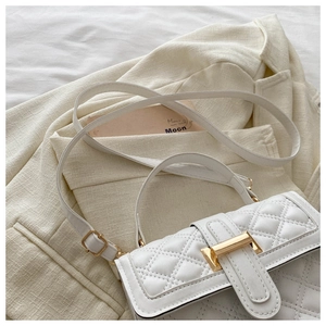 Detail of white quilted handbag featuring gold twist lock and elegant texture on blazer