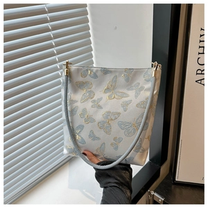 Détails de broderie dorée élégante avec motifs papillons bleus sur un sac gris
