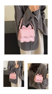 Close-up of pink bow square bag with wavy edge detail and silver chain strap