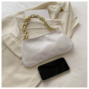 Sac sous le bras beige chic avec chaîne dorée décorative sur un blazer