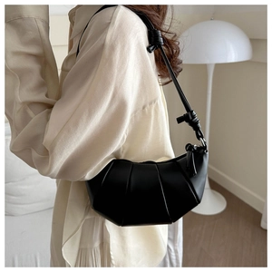 Détail latéral d'un sac croissant plissé noir avec bandoulière nouée porté par un mannequin