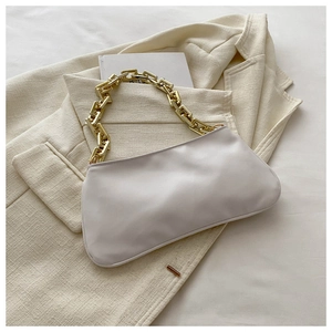 Détail d'un sac sous les bras blanc avec chaîne dorée posé sur une veste de costume