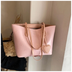 Detail of pink tote bag with pleated texture and heart-shaped pendant in minimalist setting