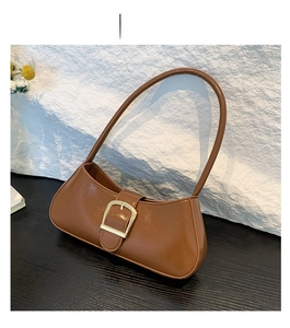 Detail view of brown glossy leather underarm bag with decorative gold square buckle