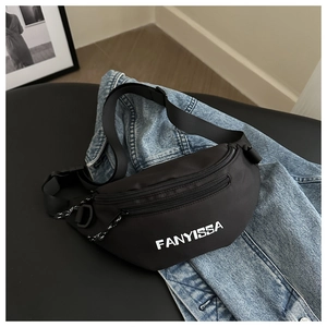 Detail of a black nylon crossbody bag with adjustable strap on a denim jacket background