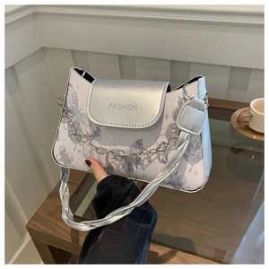Detail of silver flap handbag with butterfly print and floral metal chain accessory