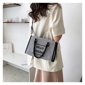 Gray canvas tote bag featuring Hello Weekend print and black leather handles shown on model