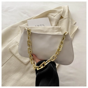 Détail du sac baguette blanc cassé avec chaîne dorée épaisse sur fond de veste de costume