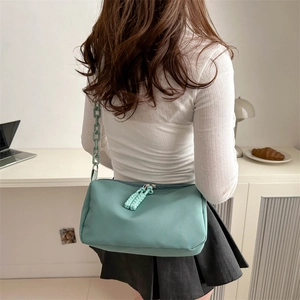 Mint green canvas crossbody bag with thick chain strap shown in an indoor office setting