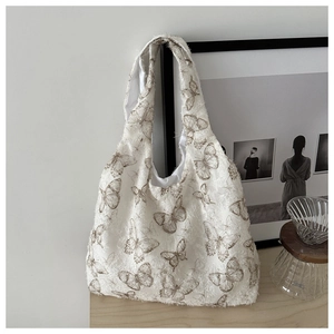 Detailed view of white lace tote bag featuring brown butterfly embroidery and wide strap
