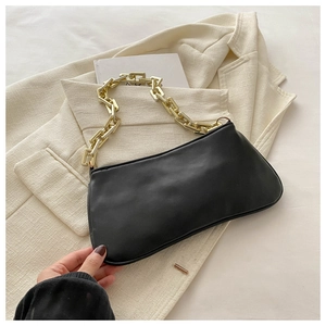 Détail du sac sous l'aisselle noir minimaliste avec chaîne dorée sur un blazer