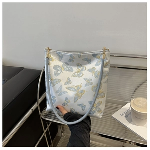 Détail du sac à bandoulière bleu clair avec broderies de papillons dorés élégants