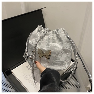 Détail d'un sac seau argenté avec texture plissée et ornement papillon métallique