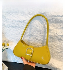 Detail view of yellow patent leather baguette bag with a stylish silver square buckle