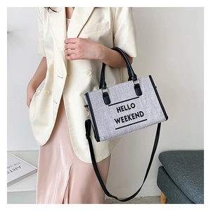 Detail of canvas tote bag with HELLO WEEKEND text and black leather straps