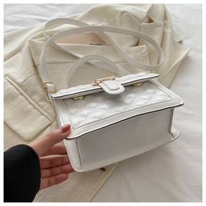 Detail showing the bottom width of the white quilted crossbody bag with golden buckle