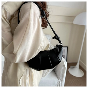 Détail d'un sac croissant noir présentant des plis verticaux et une bandoulière nouée