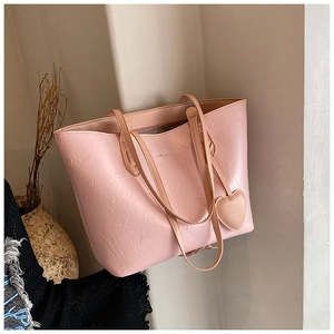 Detailed view of pink tote bag with pleated texture, dual straps and a heart charm