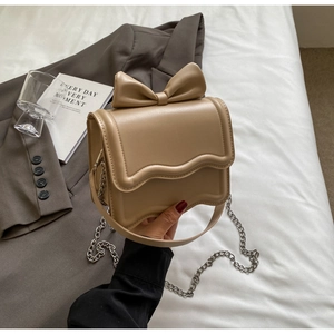 Detail of a chic cream handbag featuring a large bow and elegant wavy flap design