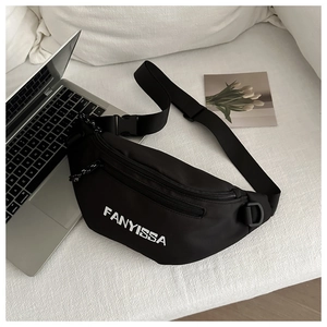 Detail of a black nylon crossbody fanny pack with FANYISSA text on a white sofa