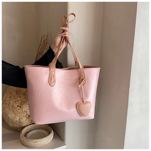 Pink tote bag detail showing pleated leather texture and a cute heart-shaped charm