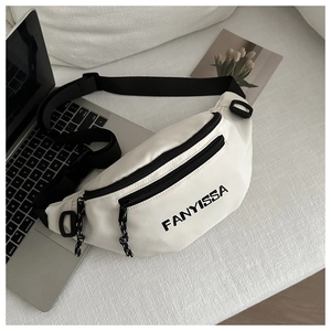 Detail of white FANYISSA crossbody bag with black zippers on a minimalist laptop background