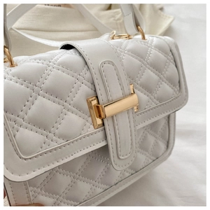 Detailed macro shot of white quilted faux leather texture with elegant gold metal clasp