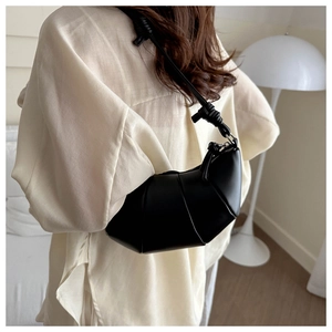 Détail du sac croissant noir avec texture plissée et sangle à nœuds élégante