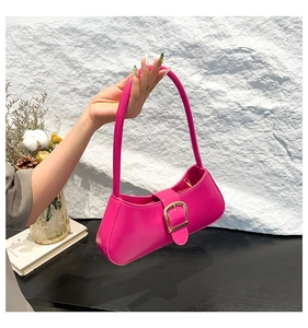 Detail of glossy pink patent leather bag showing gold buckle and sleek curved texture