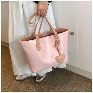 Detailed view of pink pleated leather tote bag with heart charm and crossbody strap