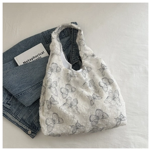 Detailed close-up of textured fabric with grey butterfly patterns on a white tote bag