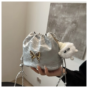 Détail du sac seau métallisé argenté avec boucle papillon et breloque en peluche