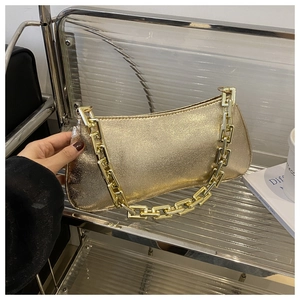 Gros plan d'un sac sous le bras doré métallisé avec une grosse chaîne sur un présentoir