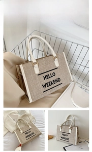 Detail of beige canvas tote bag with HELLO WEEKEND text and white leather handles