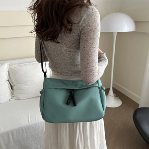 Teal large capacity nylon tote bag in minimalist utility style shown on a model
