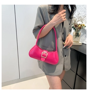 Close-up of vibrant magenta patent leather underarm bag with signature gold buckle detail