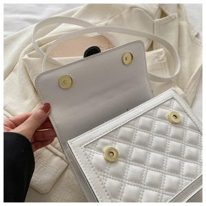 Detail of white quilted handbag showing dual gold magnetic closures and fine stitching