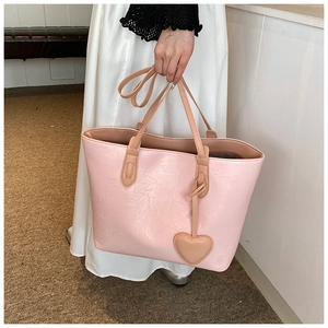 Detail of light pink tote bag with pleated texture and heart-shaped charm hanging on the side