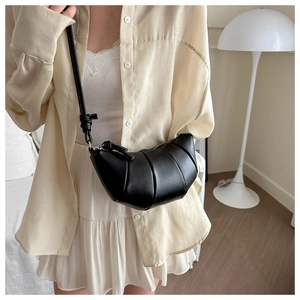 Détail d'un sac croissant noir avec matelassage plissé sur un mannequin en studio