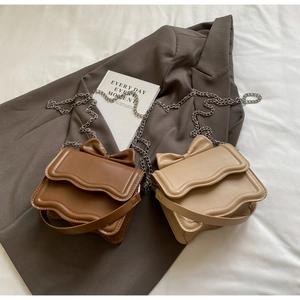 Detail of brown and beige crossbody bags with bow accent and wave-edge flap design