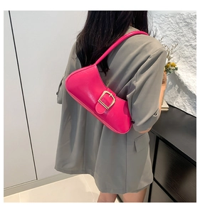 Detail of bright pink baguette bag with gold buckle on model in grey blazer