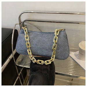 Détail du sac à bandoulière en denim bleu avec une grosse chaîne en métal doré chic