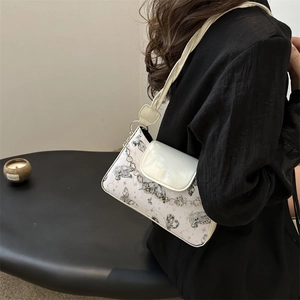 Contrast white underarm bag with butterfly print and wide shoulder strap shown on model
