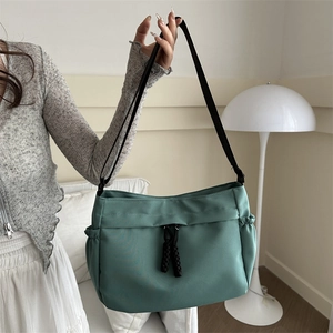 Minimalist sage green nylon tote bag with adjustable strap and side pockets for women