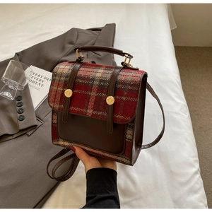 Detail of British style plaid backpack with brown faux leather straps and gold buckles