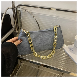 Détail du sac à bandoulière gris mat avec une chaîne en métal doré et un design minimaliste