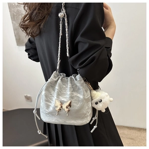 Detail of silver bucket bag with pleated texture, butterfly buckle and cat plush charm