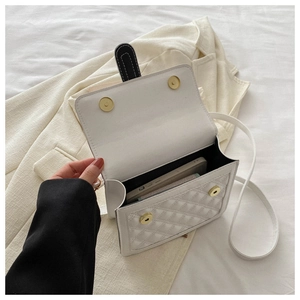 Detail of white quilted crossbody bag showing internal capacity with magnetic gold clasp