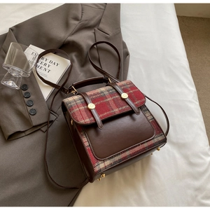 Detail of British vintage backpack with brown leather stitching and red plaid wool texture
